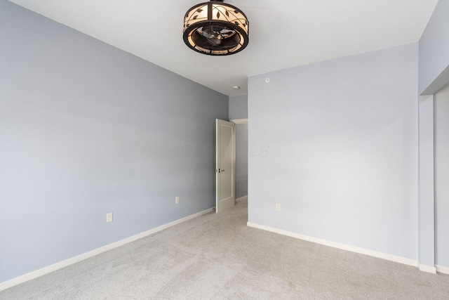 spare room with baseboards and light colored carpet