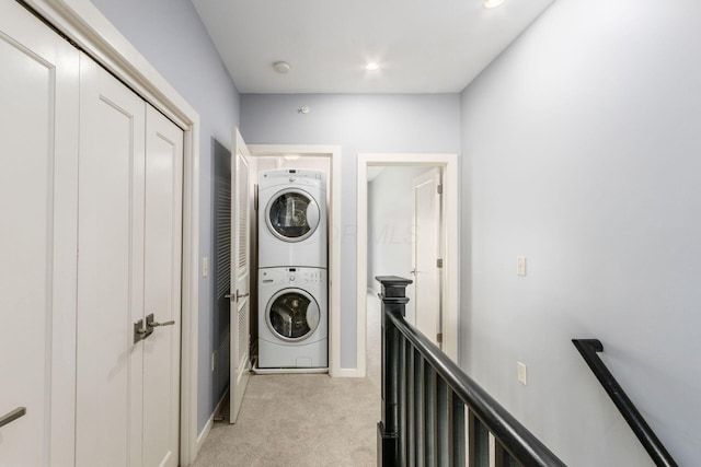 washroom featuring baseboards, stacked washer and clothes dryer, laundry area, and light colored carpet