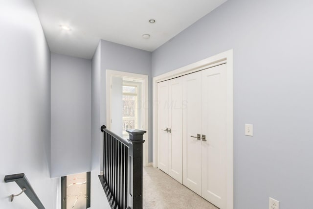corridor featuring light colored carpet and an upstairs landing