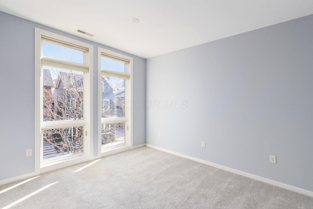 carpeted empty room featuring baseboards and visible vents