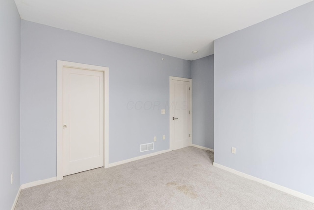 spare room with baseboards, light carpet, and visible vents