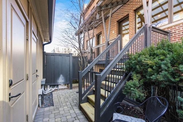 view of home's exterior featuring stairway, brick siding, fence, and a patio area