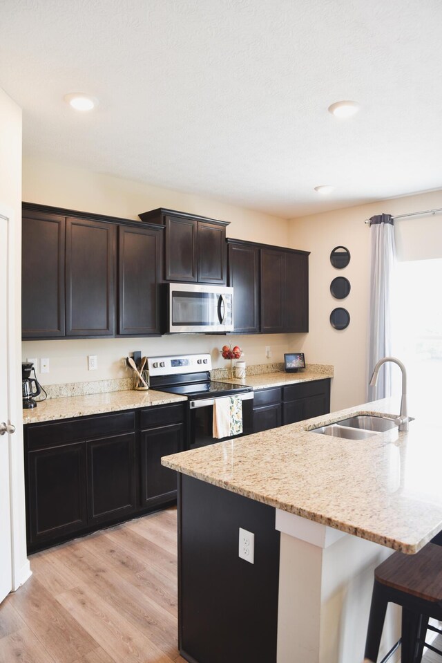 1151 Gelbray Dr, Columbus, OH 43207 - kitchen with light stone countertops, a sink, a breakfast bar area, stainless steel appliances, and light wood-type flooring