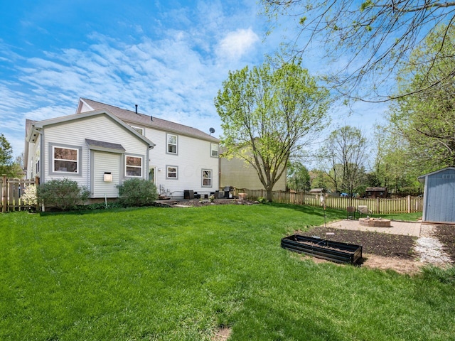 6008 Macnabb Ct, Hilliard, OH 43026 - back of house featuring a lawn, a storage unit, a fenced backyard, and an outdoor fire pit
