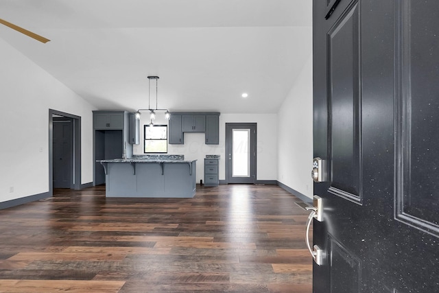 interior space with recessed lighting, light stone counters, a breakfast bar area, dark wood-style flooring, and a center island