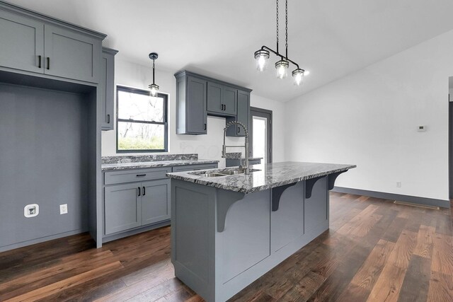 kitchen with gray cabinets, a healthy amount of sunlight, light stone countertops, and a sink