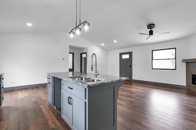 kitchen featuring dark wood-style floors, light stone countertops, a sink, and a tile fireplace
