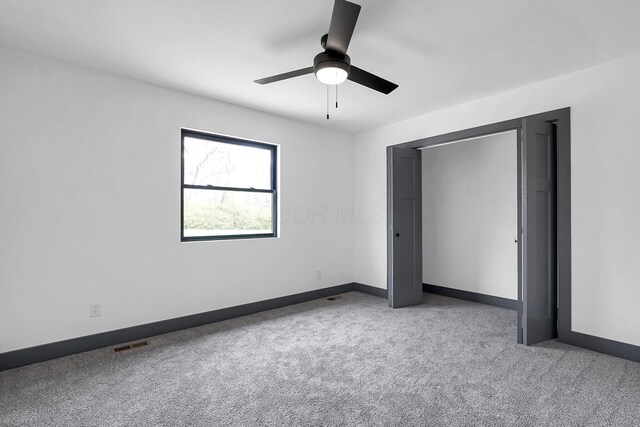 unfurnished bedroom featuring baseboards, visible vents, a ceiling fan, and carpet flooring