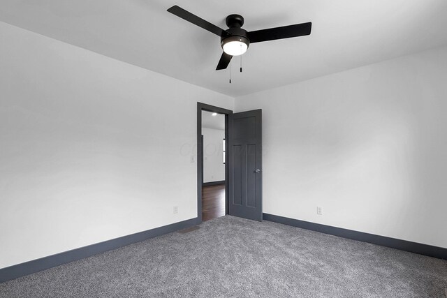 carpeted empty room with a ceiling fan and baseboards