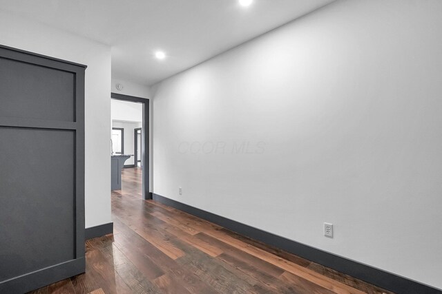 unfurnished room with recessed lighting, dark wood finished floors, and baseboards