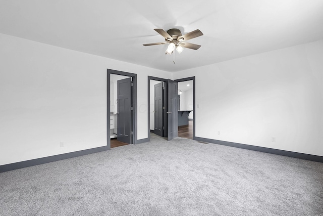unfurnished bedroom featuring baseboards, a ceiling fan, ensuite bath, and carpet floors