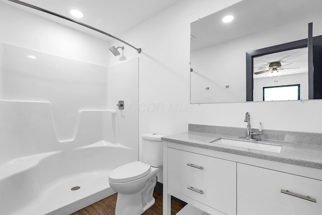 bathroom featuring wood finished floors, walk in shower, ceiling fan, toilet, and vanity