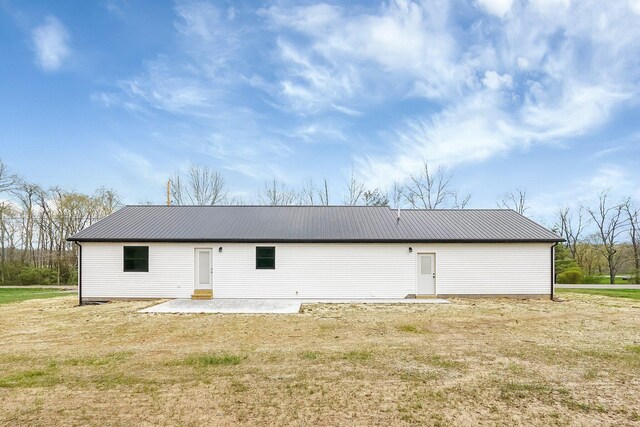 back of house featuring metal roof, a yard, and a patio area