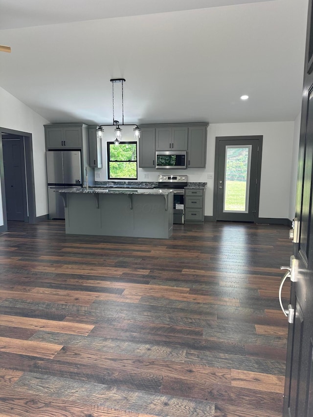 7624 Edria Ln, Athens, OH 45701 - kitchen with appliances with stainless steel finishes, gray cabinets, a breakfast bar area, dark wood-style flooring, and a center island