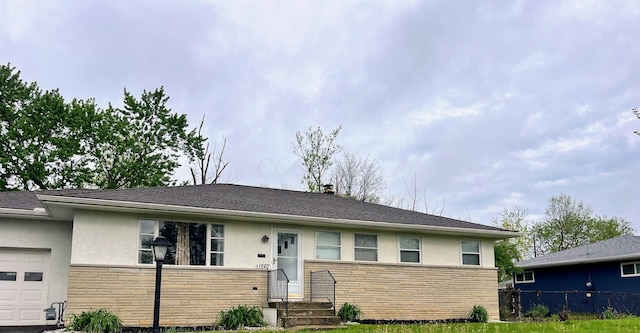 view of front of property with a garage, stone siding, stucco siding, and fence