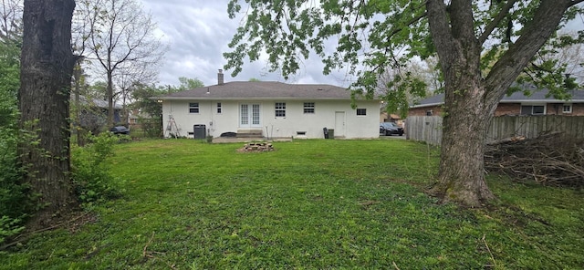 rear view of property with fence, a lawn, french doors, and stucco siding