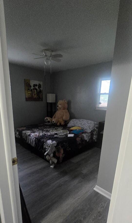 bedroom featuring a textured ceiling, wood finished floors, a ceiling fan, and baseboards