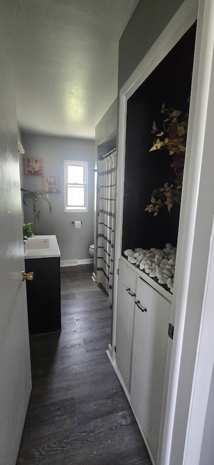 full bath featuring toilet, wood finished floors, vanity, and baseboards