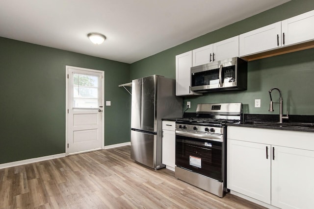 5068 Tremaine Ct, Columbus, OH 43232 - kitchen featuring stainless steel appliances, light wood-style floors, white cabinets, and dark stone countertops