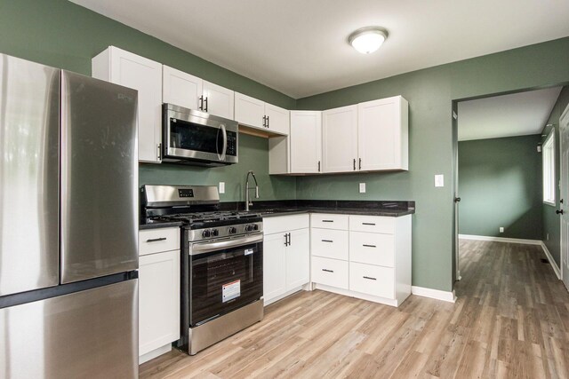 5068 Tremaine Ct, Columbus, OH 43232 - kitchen with appliances with stainless steel finishes, light wood-type flooring, dark countertops, and white cabinets