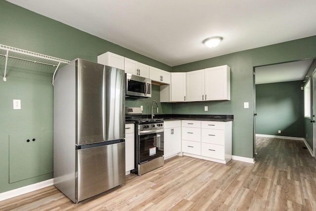 5068 Tremaine Ct, Columbus, OH 43232 - kitchen with appliances with stainless steel finishes, light wood finished floors, white cabinets, and dark countertops