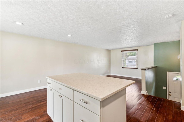 4096 Jonquil St, Columbus, OH 43224 - kitchen with dark wood-style flooring, a kitchen island, baseboards, a textured ceiling, and white cabinetry