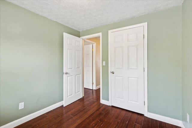 4096 Jonquil St, Columbus, OH 43224 - unfurnished bedroom with baseboards, a textured ceiling, and dark wood-style floors