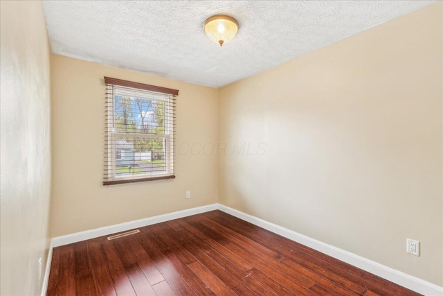 4096 Jonquil St, Columbus, OH 43224 - empty room featuring baseboards, dark wood finished floors, a textured ceiling, and visible vents