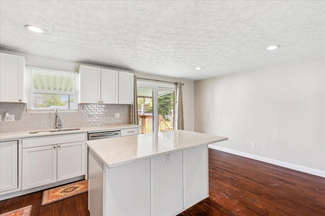 4096 Jonquil St, Columbus, OH 43224 - kitchen with decorative backsplash, a center island, a sink, baseboards, and dark wood-type flooring