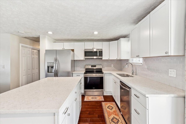 4096 Jonquil St, Columbus, OH 43224 - kitchen with a kitchen island, appliances with stainless steel finishes, dark wood finished floors, a sink, and white cabinetry