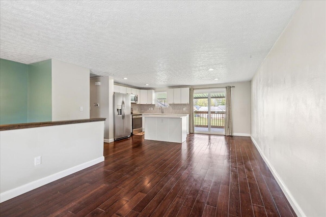 4096 Jonquil St, Columbus, OH 43224 - unfurnished living room with dark wood-type flooring, a sink, a textured ceiling, and baseboards