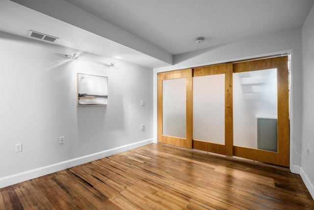 unfurnished bedroom with visible vents, baseboards, and hardwood / wood-style flooring