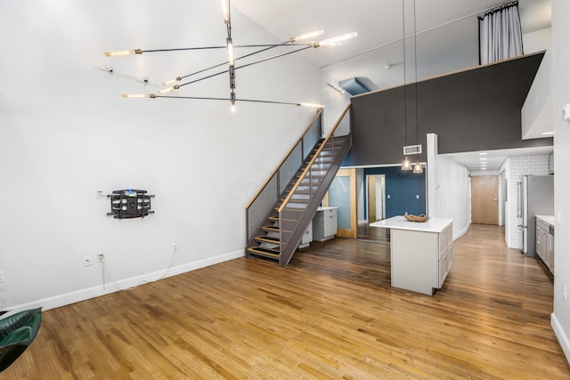 kitchen featuring freestanding refrigerator, baseboards, wood finished floors, and a towering ceiling