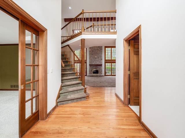 interior space featuring a towering ceiling, wood finished floors, baseboards, carpet floors, and stairs