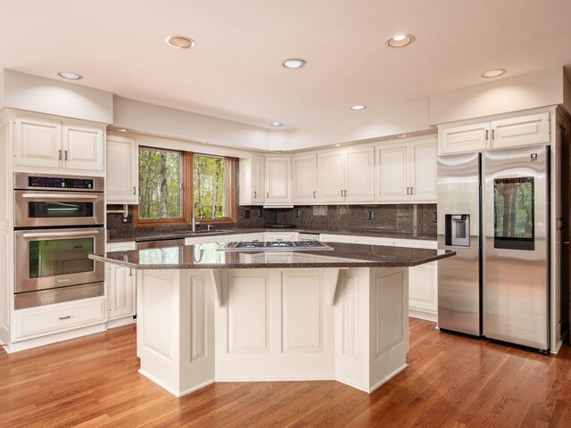 kitchen featuring dark stone counters, white cabinetry, appliances with stainless steel finishes, and a sink