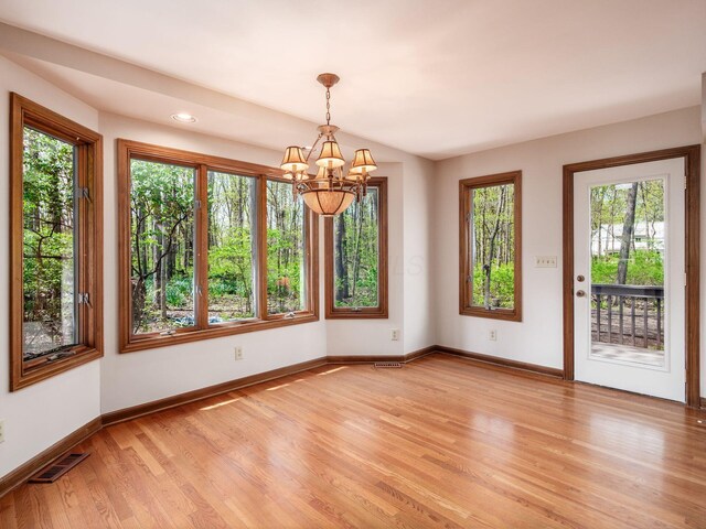 unfurnished dining area with visible vents, light wood-type flooring, baseboards, a notable chandelier, and recessed lighting