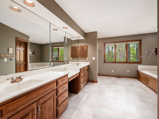 full bath with vanity, baseboards, plenty of natural light, and a garden tub