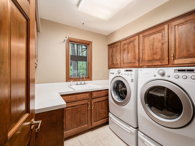 laundry room with a sink, light tile patterned floors, cabinet space, and washing machine and clothes dryer