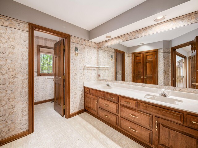 full bathroom featuring double vanity, baseboards, a sink, and tile patterned floors