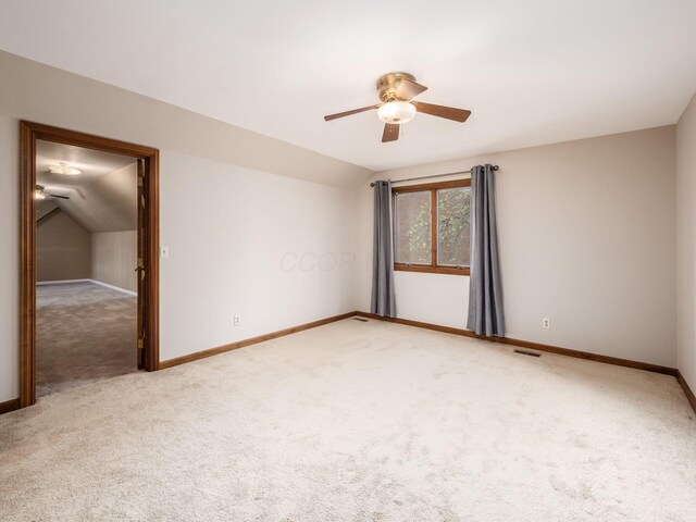 spare room with ceiling fan, light colored carpet, baseboards, lofted ceiling, and visible vents