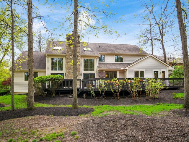 back of property featuring a chimney, a shingled roof, and a wooden deck