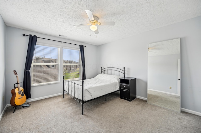bedroom with a textured ceiling, visible vents, carpet flooring, and baseboards
