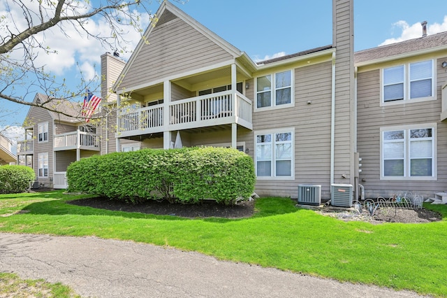 back of property featuring a lawn, a chimney, and central AC