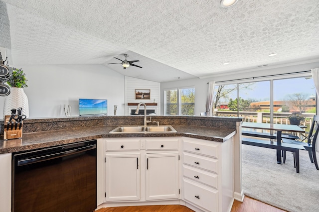 kitchen featuring black dishwasher, ceiling fan, dark countertops, and a sink