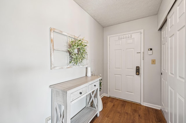 doorway to outside featuring a textured ceiling, dark wood finished floors, and baseboards
