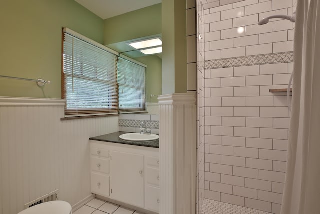 2589 Brookwood Rd, Columbus, OH 43209 - bathroom featuring a wainscoted wall, tiled shower, vanity, tile patterned floors, and toilet