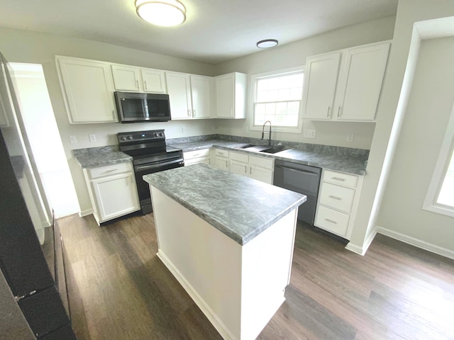 kitchen with stainless steel microwave, a sink, dishwashing machine, dark wood finished floors, and black / electric stove