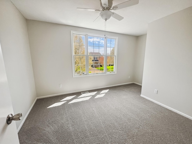 carpeted empty room with ceiling fan, visible vents, and baseboards