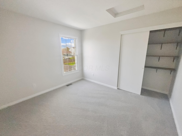 unfurnished bedroom featuring baseboards, visible vents, a closet, and carpet