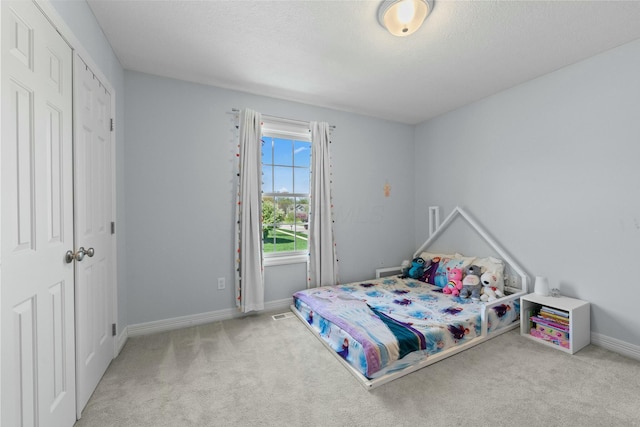 carpeted bedroom featuring a textured ceiling, baseboards, and a closet